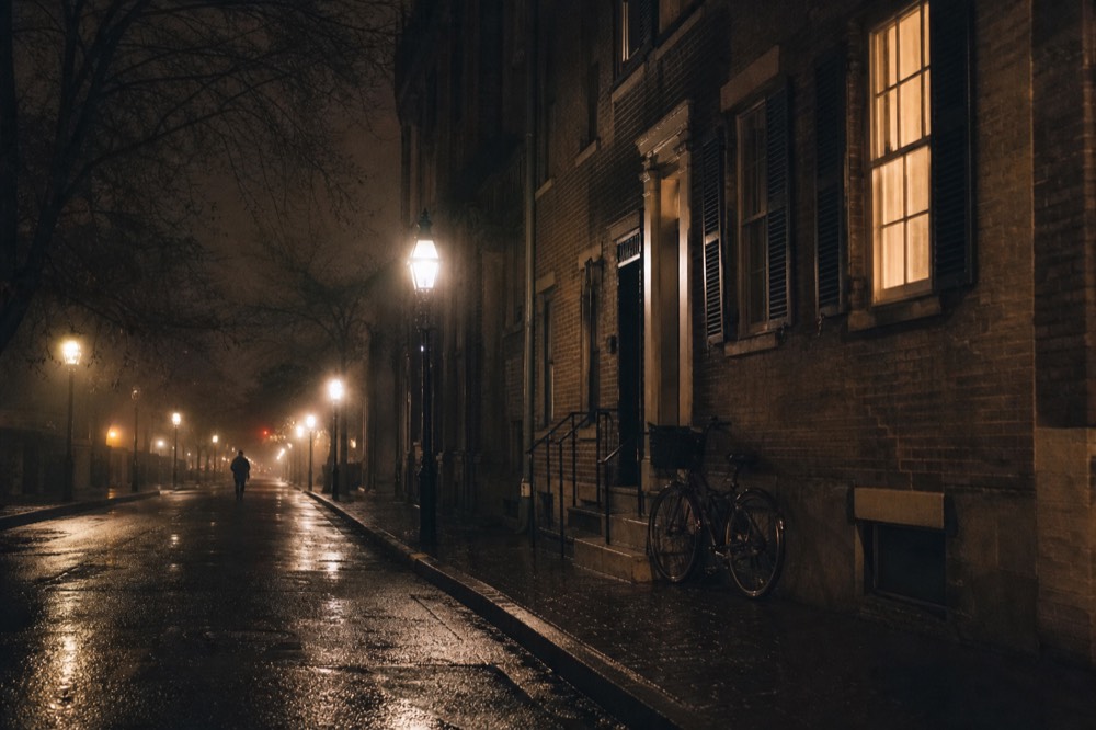 A lamplit Savannah street with historic brick buildings at night, no text, no logos, no people