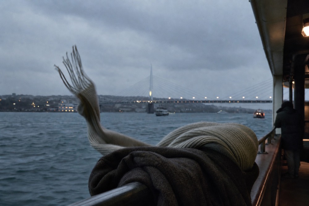 A warm jacket and scarf draped over a riverboat rail at dusk in cool weather, no text, no logos, no people