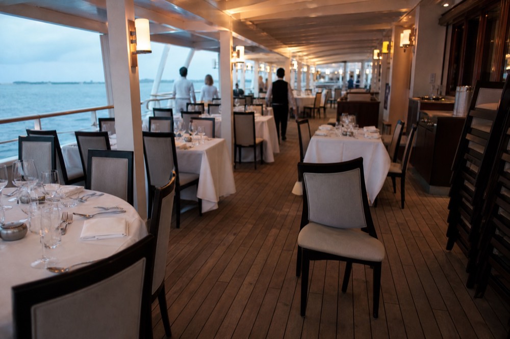 Interior dining deck of a riverboat set with banquet tables, no text, no logos, no people