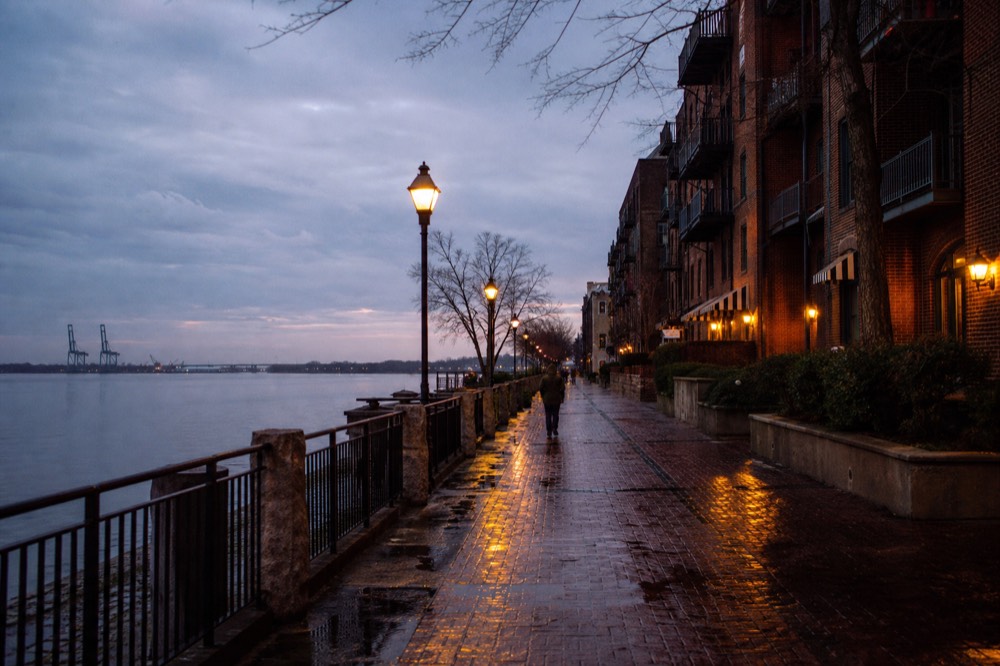 Riverfront promenade in Savannah with cotton warehouse buildings at dusk, no text, no logos, no people