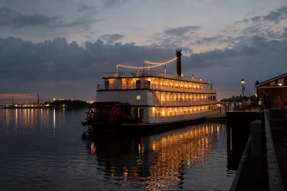 A dinner riverboat lit up at dusk on the Savannah River, no text, no logos, no people