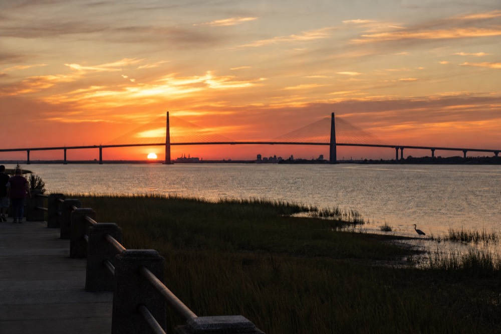 A clear orange sunset sky over the Savannah River with the bridge silhouette on the horizon, no text, no logos, no people