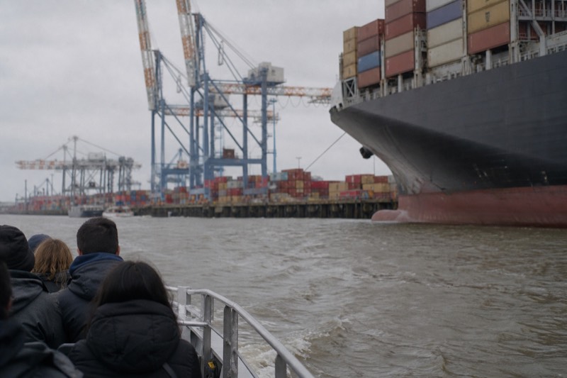 A tour boat passing container ships and cargo cranes on the working stretch of the Savannah River, on the Savannah River